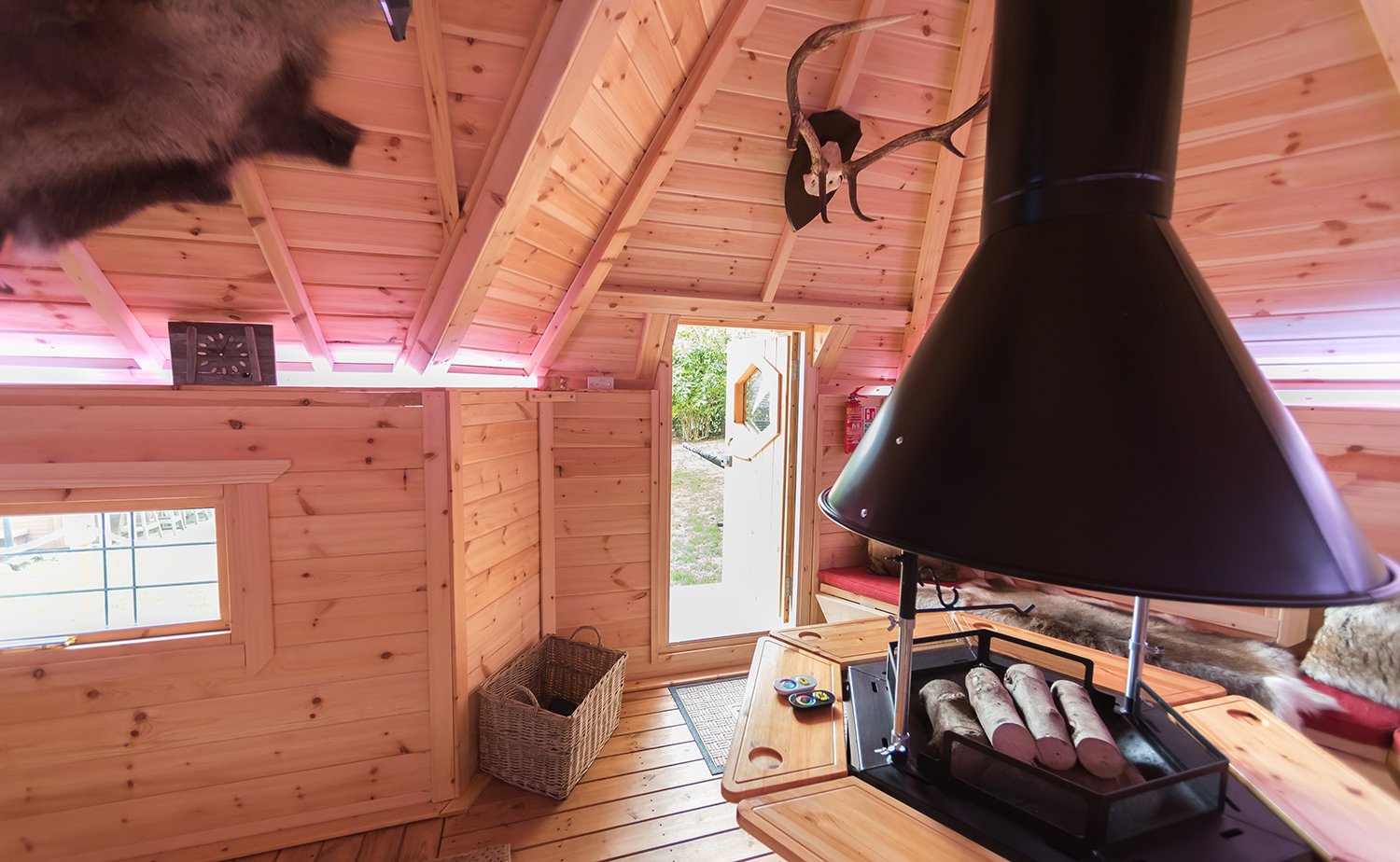 Inside a timber forest school cabin with BBQ unit with logs on