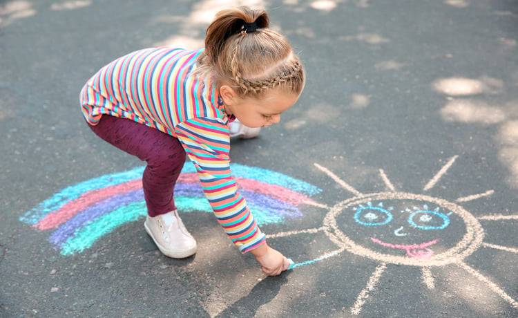 Photo of young child playing on school playground with chalk