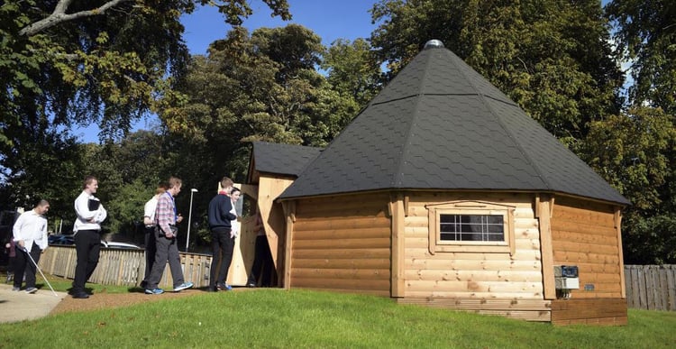 Large timber cabin with pupils entering through door