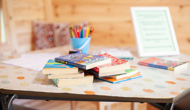 Interior of a timber School Cabin, close up shot of table with children's books and coloured pencils