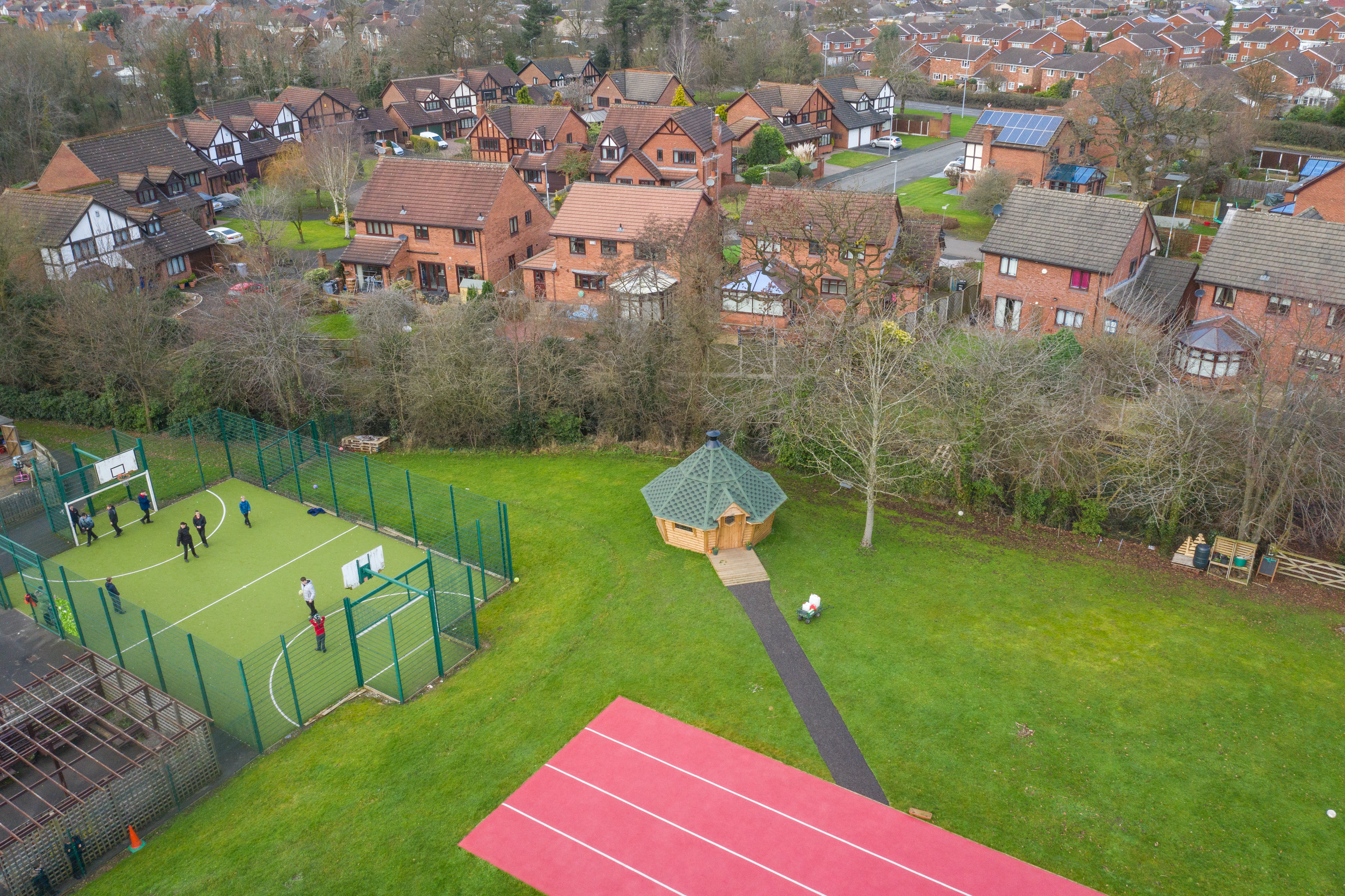 Overhead shot of a school log cabin with green roof next to school tennis courts