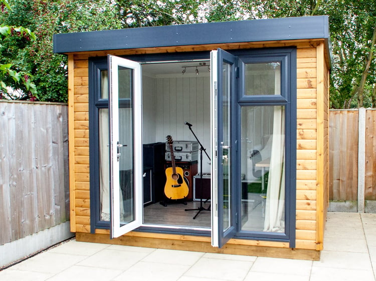 Small Music Room in corner of garden with open doors and guitar, microphone and music equipment
