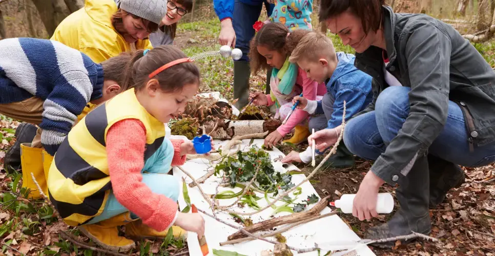 Children enjoying forest school outdoor activities with teachers 